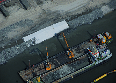 Bagger beladen Boot mit Schotter
