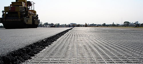 Frischer Asphalt verdichtet mit Walze und Bitumenbeschichtung für optimalen Haftverbund Verdichtung von frischem Asphalt mit Walze und Bitumenbeschichtung für starken Haftverbund